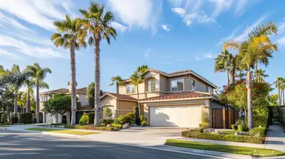 Two-story Southern California homes with tile roofs, palm trees and driveways on a sunny suburban street